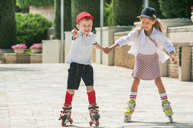 Portrait of a charming teenage couple skating together on roller skates at park.