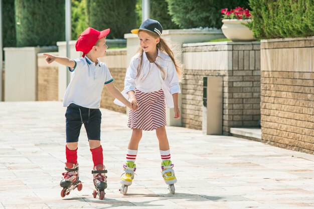 Portrait of a charming teenage couple skating together on roller skates at park.