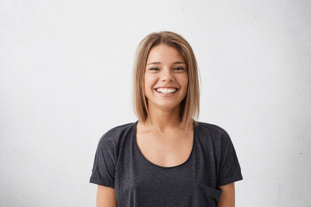 Portrait of cheerful beautiful woman with trendy hairdo having dark charming eyes and engaging smile. People, happiness, emotions and lifestyle concept