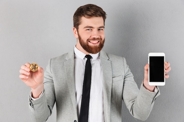 Free photo portrait of a cheerful businessman holding bitcoin