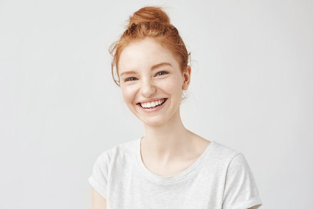 Portrait of cheerful redhead woman with hair bun laughing.