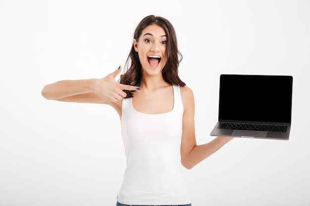 Portrait of a cheerful woman dressed in tank-top pointing finger