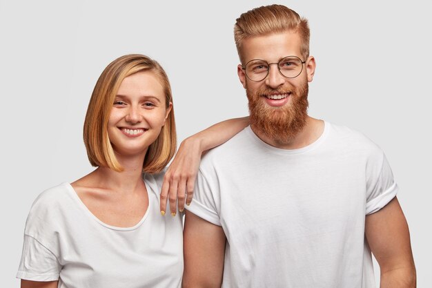 Portrait of cheerful young woman and man friends have fun together, dressed in casual outfit, isolated over white wall