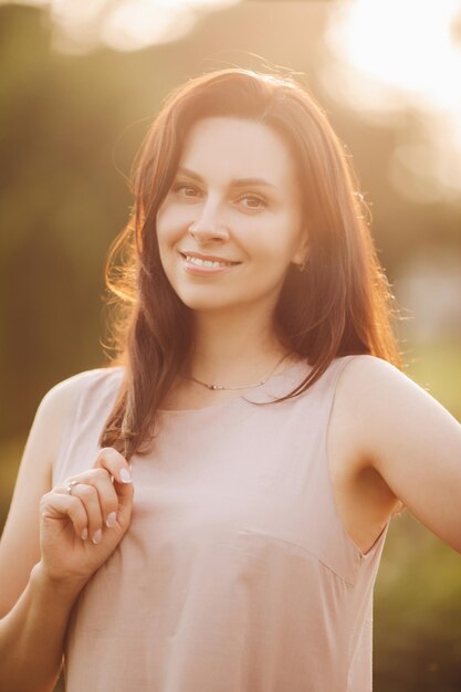 Portrait of cheerful young woman with dark hair walking in the garden