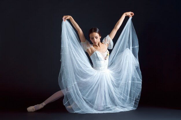 Portrait of classical ballerina in white dress on black