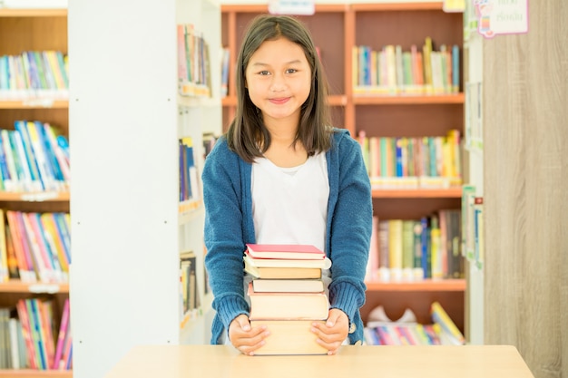 Portrait of clever student with open book reading it in college library