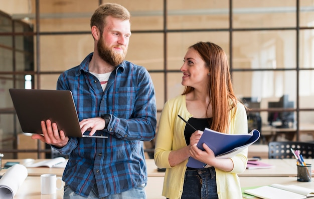 Free photo portrait of colleagues looking at each other and smiling in office