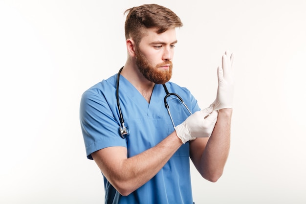 Free Photo portrait of a concentrated young doctor putting on sterile gloves