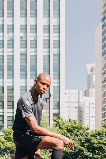 Free photo portrait of a confidence athlete young man looking at camera standing against building