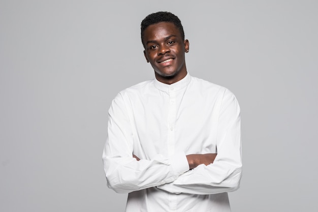 Portrait of confident  afro man dressed in white classic shirt with folded hands isolated on gray background