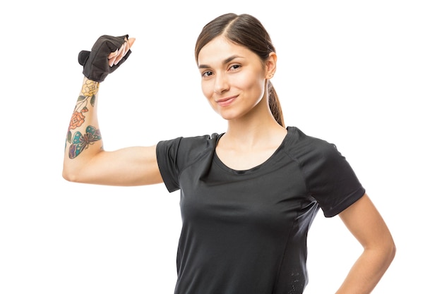 Free photo portrait of confident athletic female flexing her biceps over white background