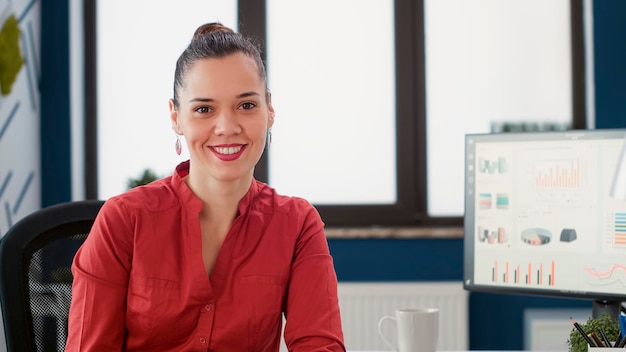 Portrait of confident business woman with executive job working with management and marketing statistics on computer. Office worker analyzing research charts and data reports.