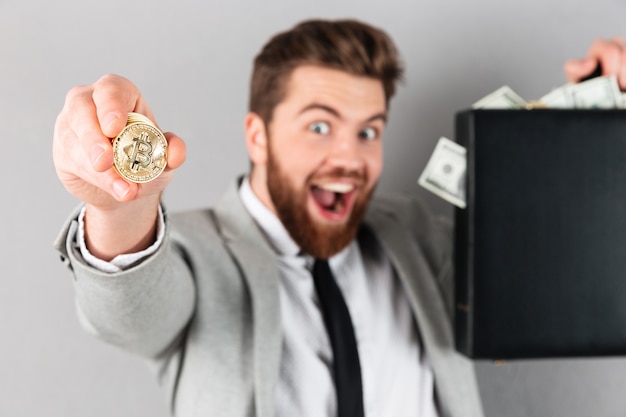 Free Photo portrait of a confident businessman showing golden bitcoin