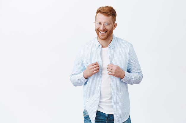 Free photo portrait of confident and happy handsome redhead guy with bristle, touching shirt with self-assured and uplifted expression, smiling broadly