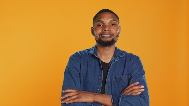 Free Photo portrait of confident person smiling on camera against orange background