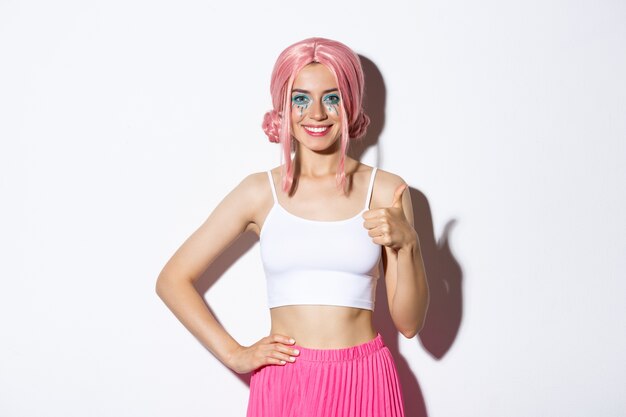 Portrait of confident smiling party girl celebrating halloween, showing thumbs-up in approval