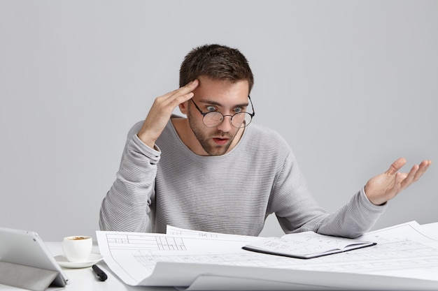 Portrait of confused male designer or architect, feels stressed, being nervous