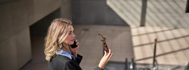 Free Photo portrait of corporate woman standing on escalator making a phone call using smartphone walking in