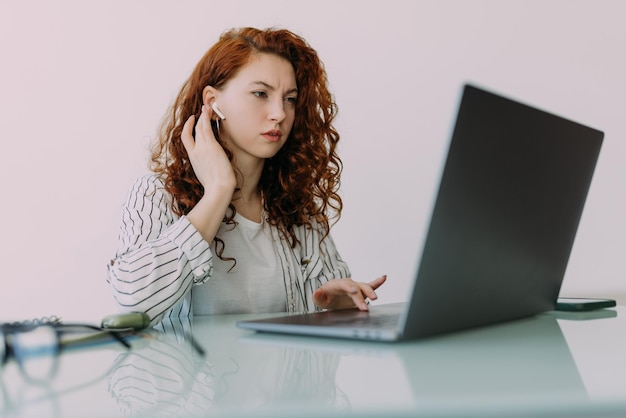 Portrait of curly young businesswoman in a headset holding the microphone attentive customer service representative responding to customer inquiry Female employee in headphones talking