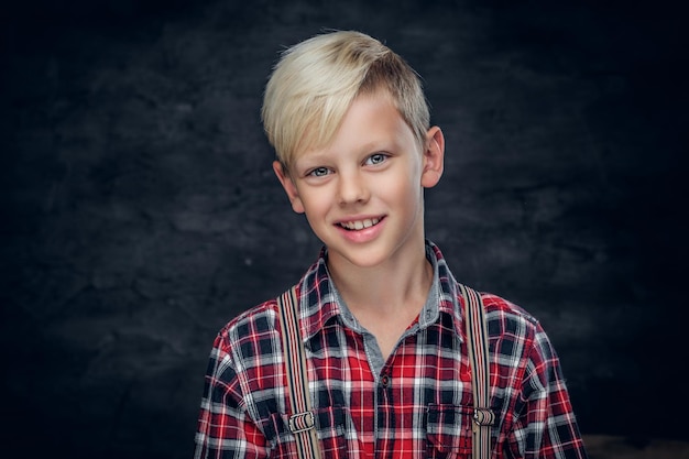 Free photo portrait of cute blonde teenage boy in a shirt on grey background.