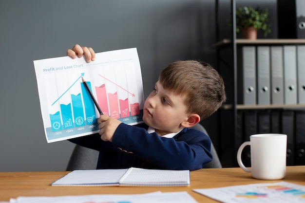 Free photo portrait of cute boy showing graph at his office desk