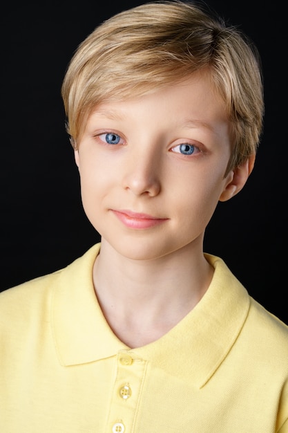 Free Photo portrait of a cute boy in a yellow t-shirt on a black background posing for the camera