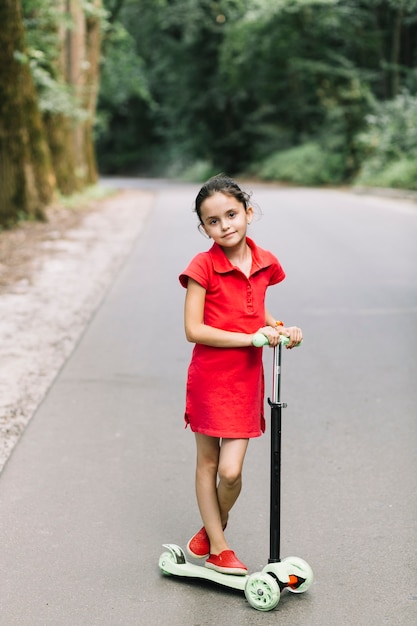 Free photo portrait of a cute girl standing over scooters on road