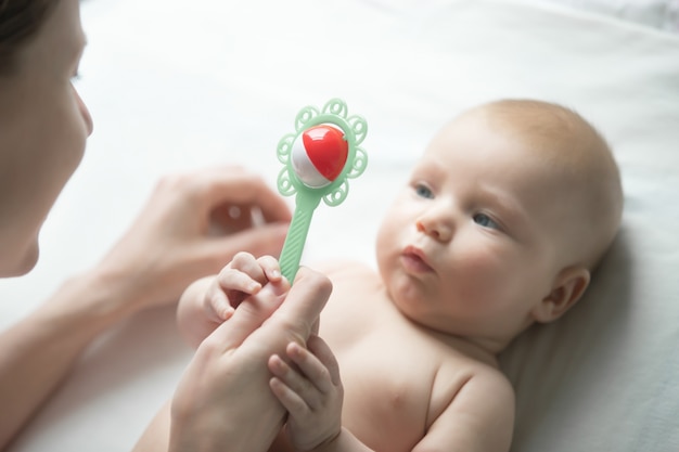 Portrait of a cute newborn looking at mother's hand with a rattle