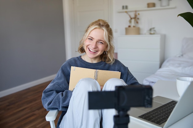 Portrait of cute smiling young social media content creator girl records video on digital camera and