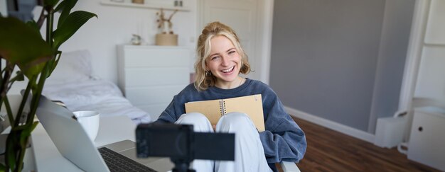 Portrait of cute smiling young social media content creator girl records video on digital camera and