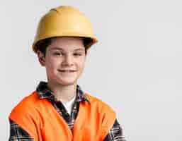 Free photo portrait of cute young boy posing with hard hat