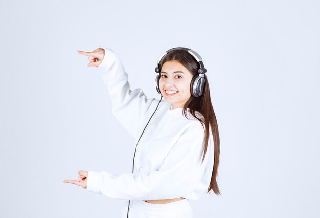 Portrait of a cute young girl model standing with headphones .