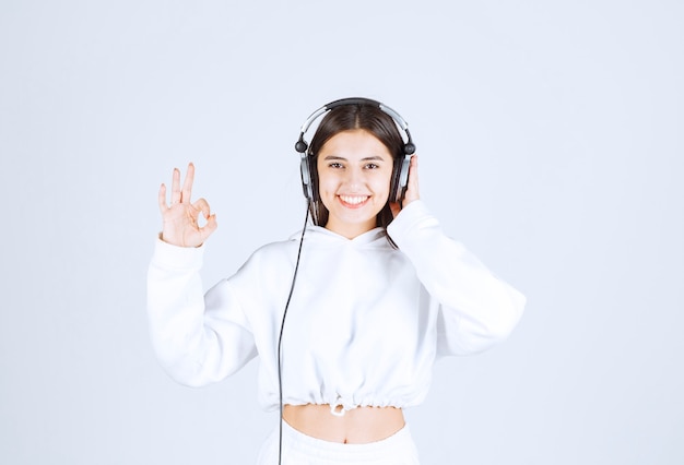 Free Photo portrait of a cute young girl model with headphones showing silent sign .