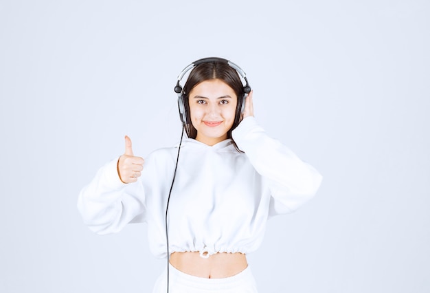 Free Photo portrait of a cute young girl model with headphones showing a thumb up .