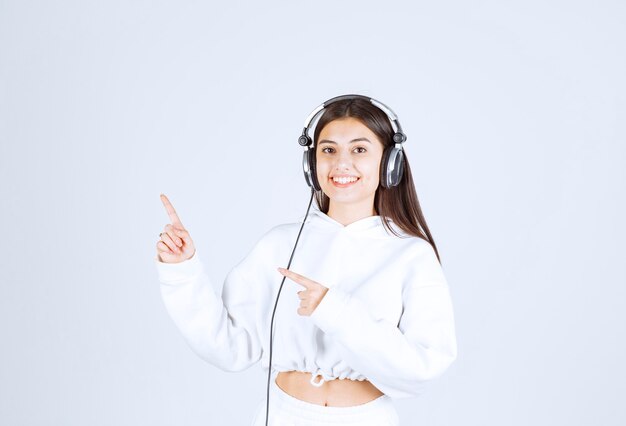 Portrait of a cute young girl model with headphones showing a thumb up .