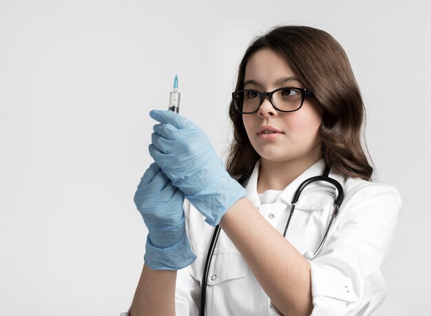 Portrait of cute young girl with syringe and surgical gloves