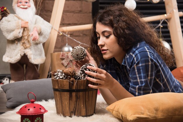 Portrait of a cute young woman looking in a wooden basket of pinecones 