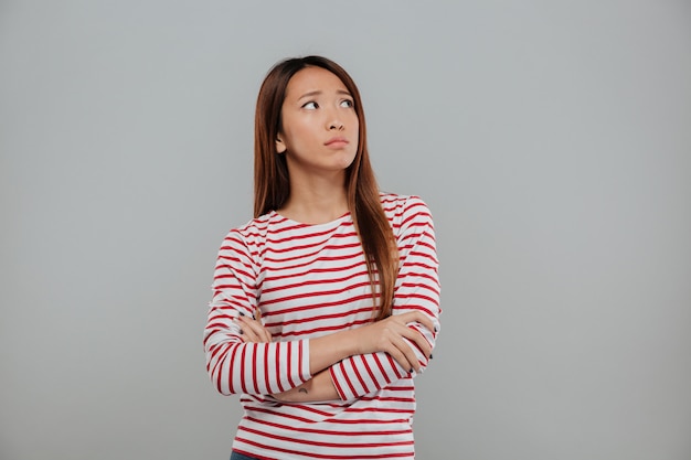 Portrait of a depressed asian woman standing with arms folded