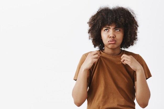 Portrait of displeased gloomy and bothered cute african american woman in brown t-shirt breathing out and looking up on sun with dislike of weather