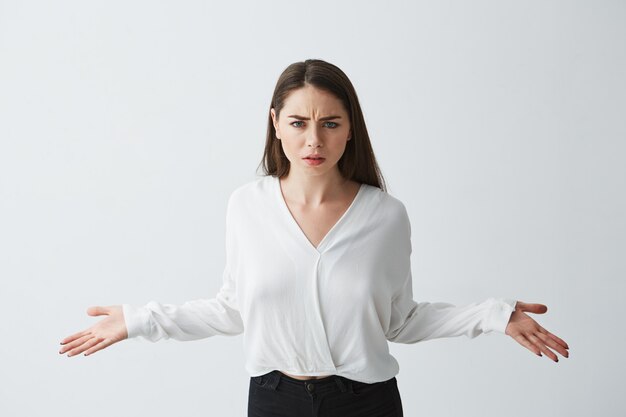 Portrait of displeased young businesswoman spreading hands out .