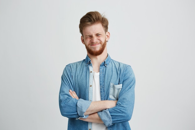 Free photo portrait of displeased young handsome man in jean shirt with crossed arms.