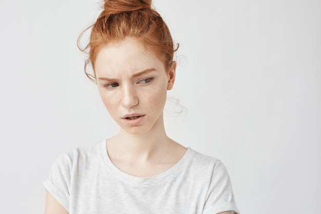 Portrait of dissatisfied redhead woman with freckles.