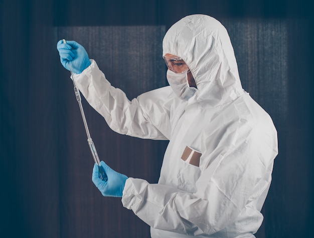 Portrait of a doctor taking medicine samples with mask, gloves and protective suit