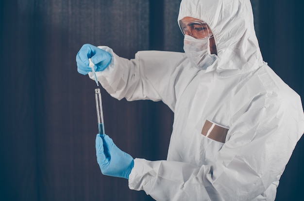 Portrait of a doctor taking medicine samples with mask, gloves and protective suit