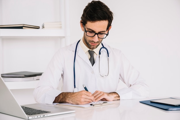 Free photo portrait of a doctor writing on clipboard in clinic