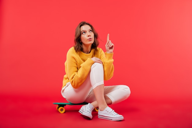 Free Photo portrait of an excited girl sitting on a skateboard