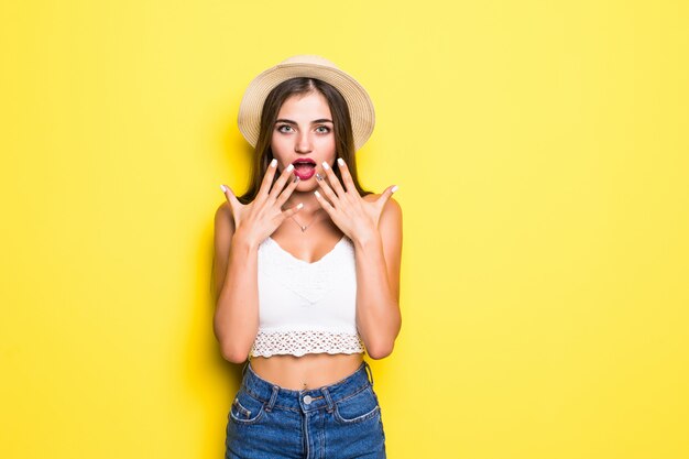 Portrait of excited screaming young woman standing isolated over yellow wall.