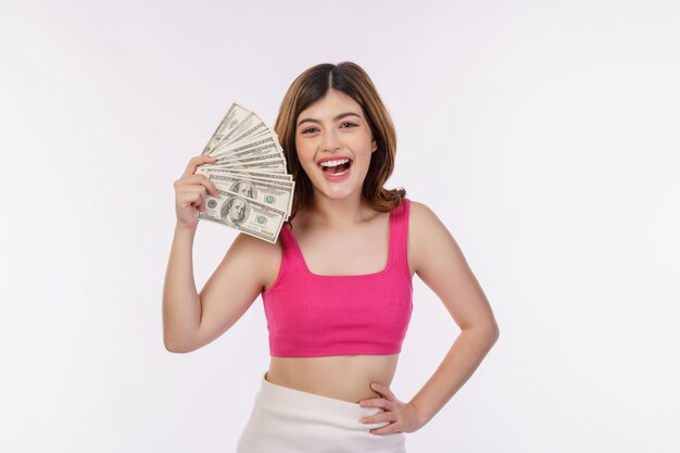 Portrait of excited young woman holding bunch of dollars banknotes isolated over white background