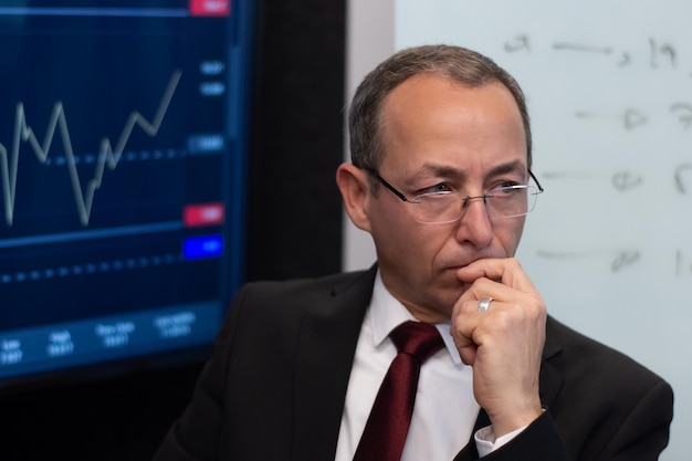 Free photo portrait of experienced financial expert in office. serious and thoughtful man working on his workplace analyzing financial data of stock market enjoying thinking. financial analytics, business strate