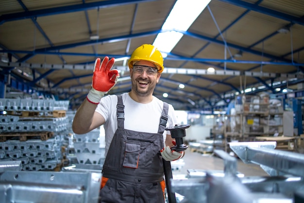 Free photo portrait of factory worker in protective equipment holding thumbs up in production hall